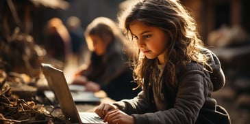 a child sitting on a bench using a laptop