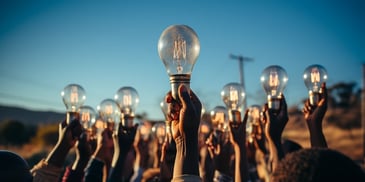 a group of hands holding a light bulb