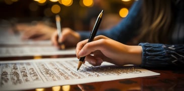 a person writing on paper with a pen