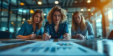 Three businesswomen working together on documents at a table in a modern office