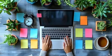 Hands on laptop surrounded by sticky notes.
